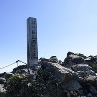 谷川岳オキの耳の山頂で立つ山頂標と石積みの写真