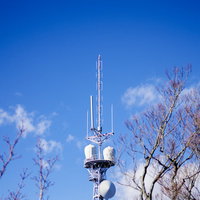 筑波山に立つ白い鉄塔の先端とアンテナ設備の写真