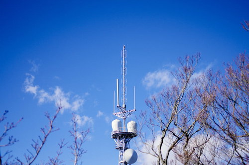 筑波山に立つ白い鉄塔の先端とアンテナ設備