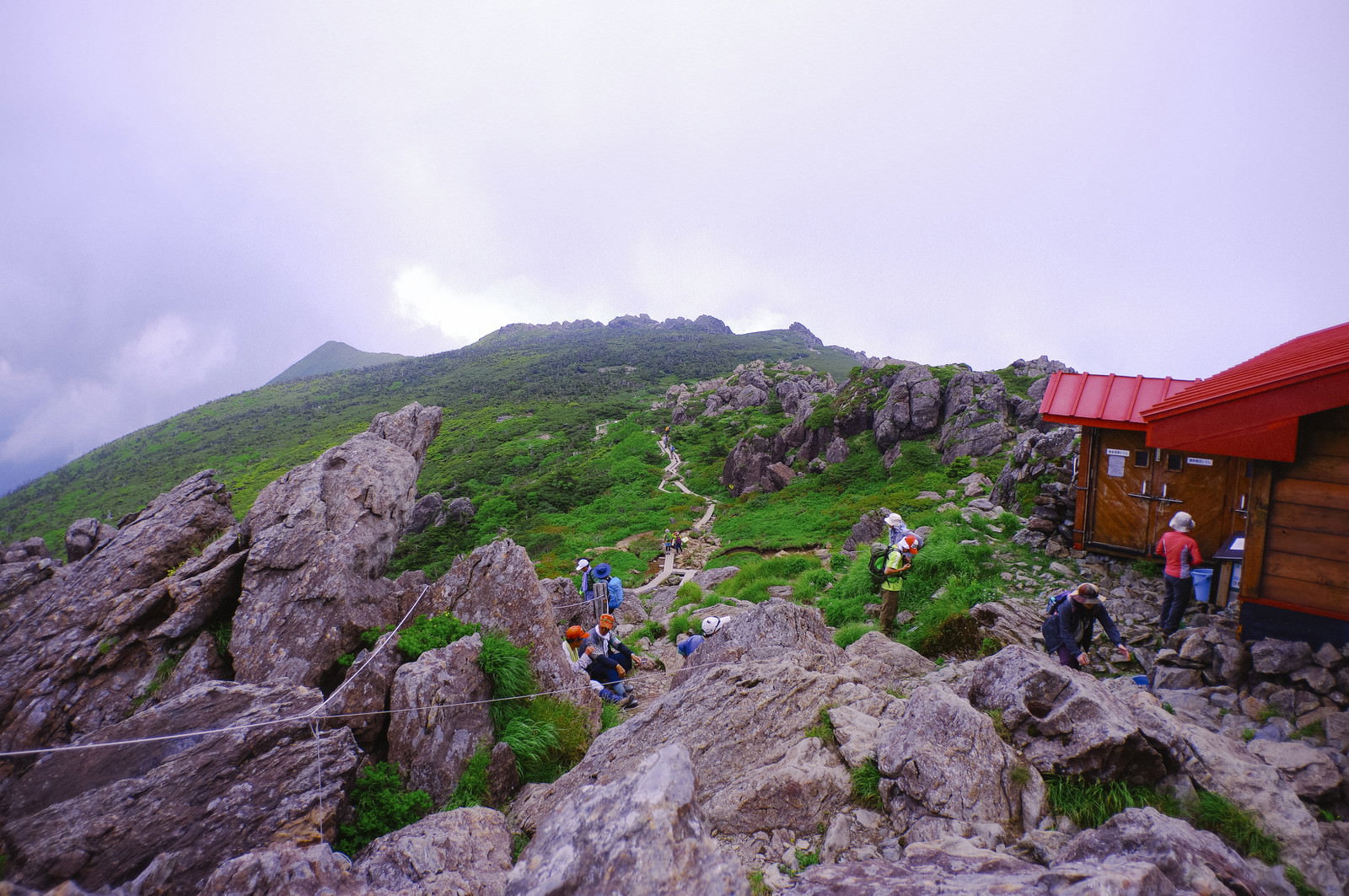 早池峰山の岩場の山頂で赤いテントの前で休憩する登山者たち