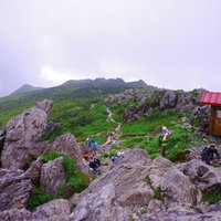 早池峰山の山頂で休む登山者たちと山小屋の風景の写真