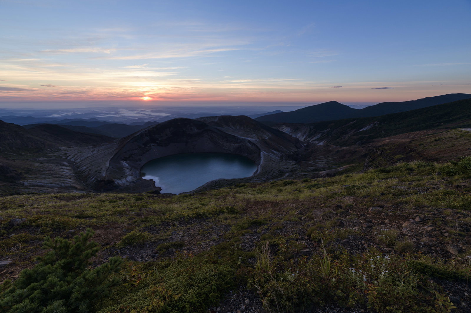 朝焼けの空の下で青い水面を湛える蔵王のお釜火口湖