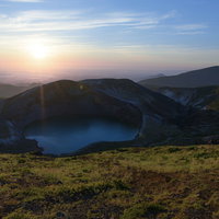 朝日に照らされる蔵王のお釜、神々しい太陽の光差す夏の山景の写真