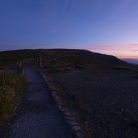 朝焼けに染まる蔵王の稜線をどこまでも走る登山道の写真
