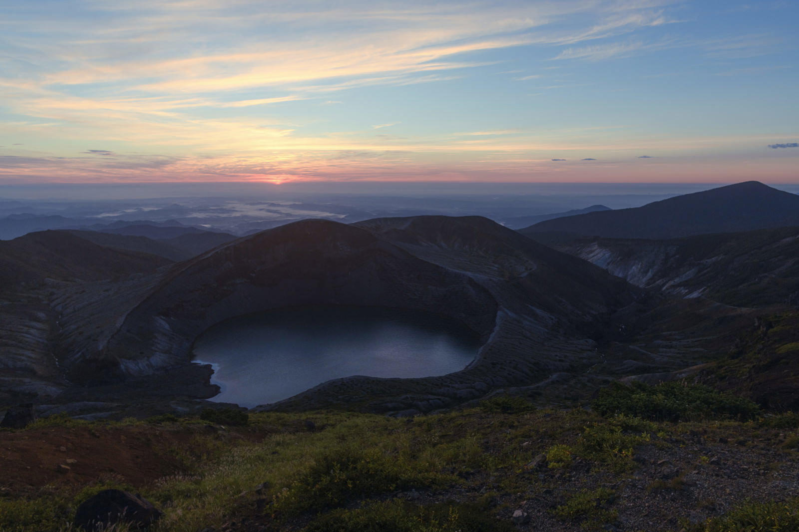 薄明の空の下、蔵王お釜の火口湖が静かに佇む山岳風景
