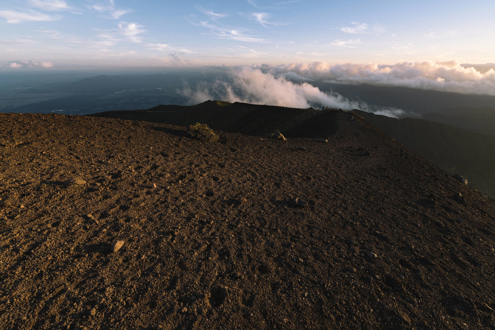 夕日に照らされ赤く染まった岩手山山頂のおはち火口と荒地