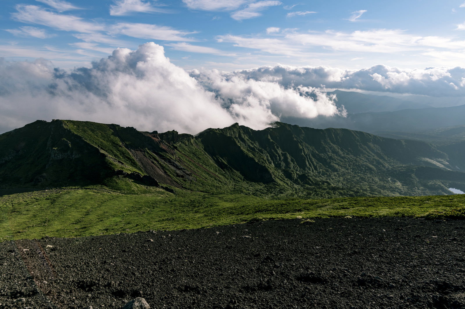 雲海に包まれた緑の山稜と青空が広がる岩手山鬼ヶ城コースの風景