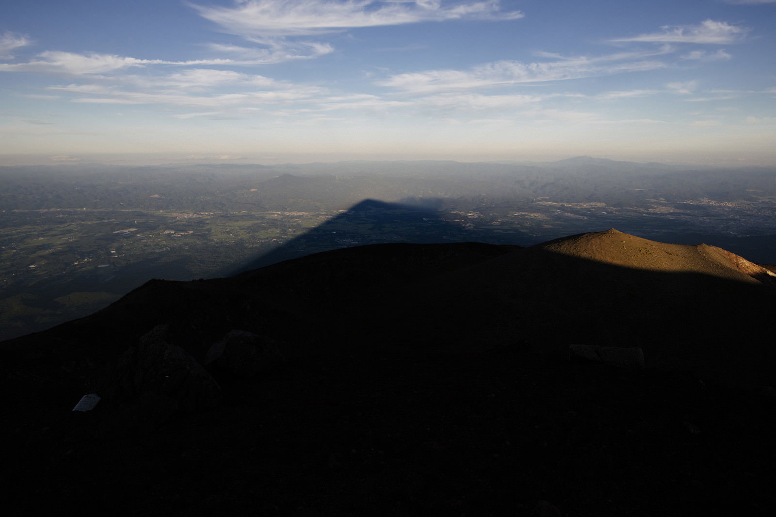 夕日を背景に岩手山のシルエットが平野部に影富士を作り出している風景