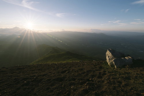 夕日の光芒に照らされる岩手山山頂の岩場と鬼ヶ城コース方面