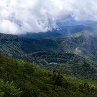 山頂から見下ろす御釜湖と雲がかかる日本百名山・岩手山の写真