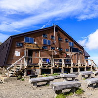 岩手山8合目小屋で休憩する登山者たち、青空と雲の景色の写真