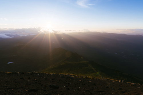 岩手山の山頂に照り付ける夕日と雲間の光芒