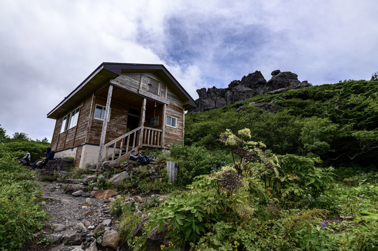 緑の山肌を背景に佇む平笠不動避難小屋の木造建築