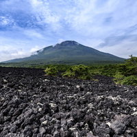 麓から見上げる岩手山の黒い岩肌と青空の絶景の写真