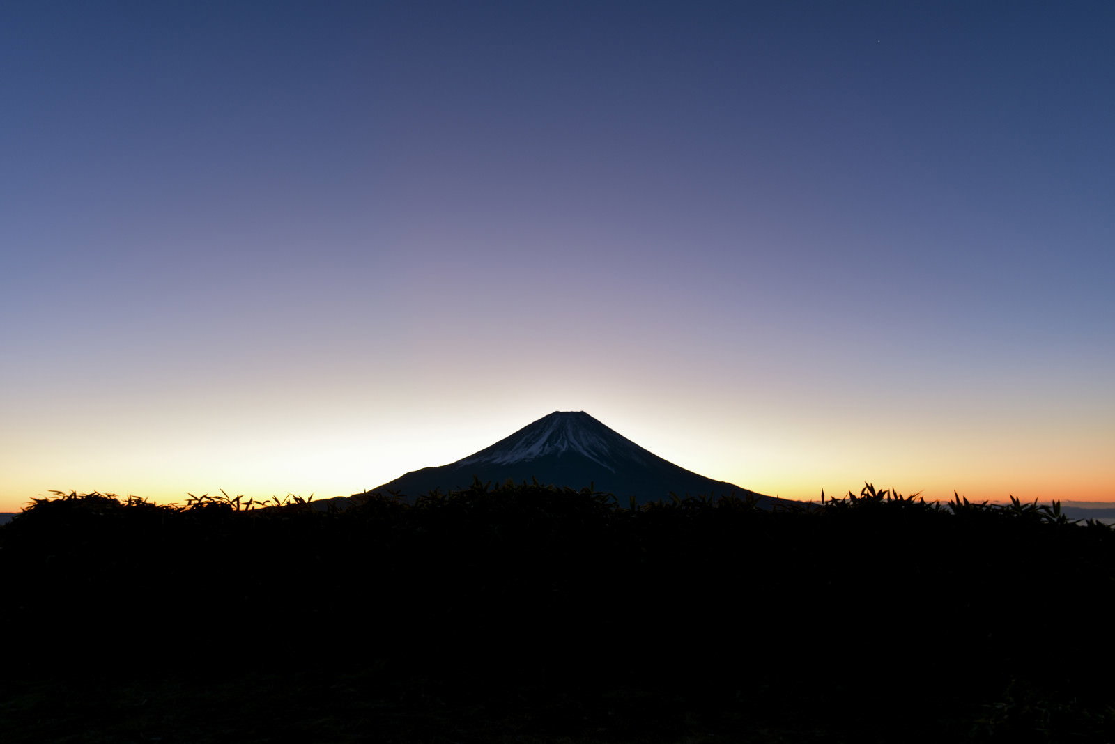 朝焼けを待つ富士山のシルエットが薄明の空に浮かぶ風景