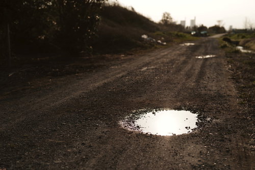 夕日を反射する農道の砂利道にできた水たまり