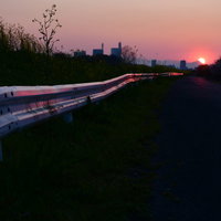 夕日に照らされた道路のガードレール - 夕焼け風景の写真