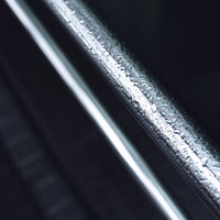 雨に濡れた金属製の手摺りに輝く水滴と光の反射の写真