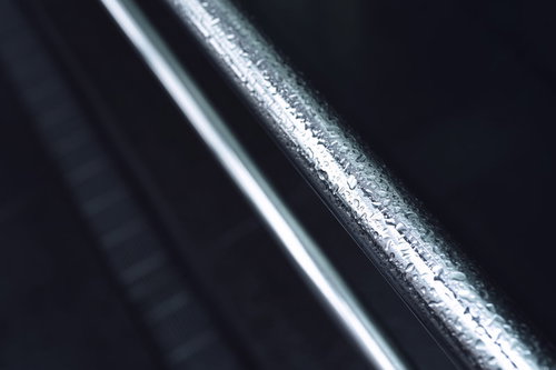 雨に濡れた金属製の手摺りに輝く水滴と光の反射