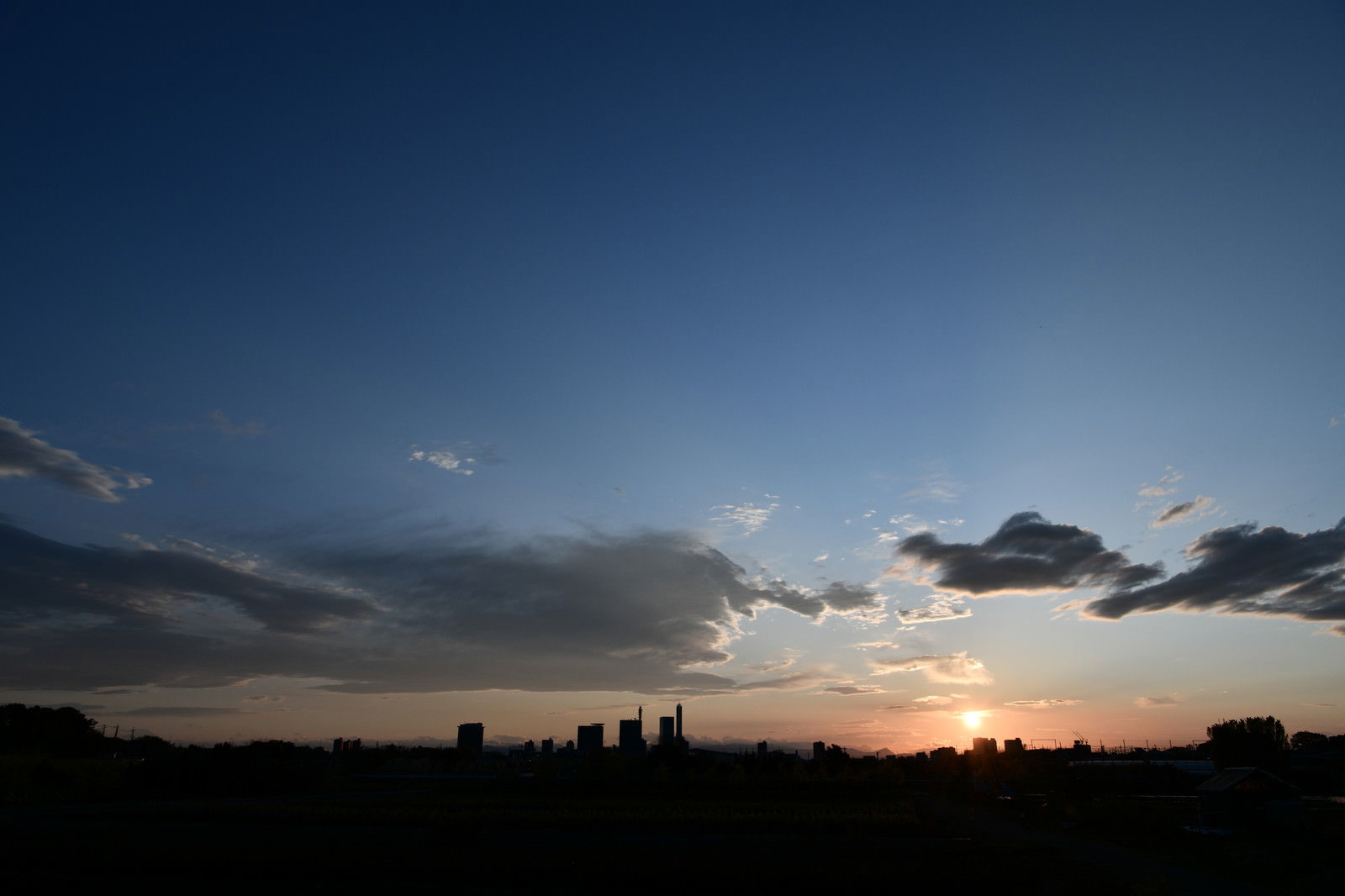 オレンジ色の夕焼け空と建物のシルエットが写る地方都市の夕景