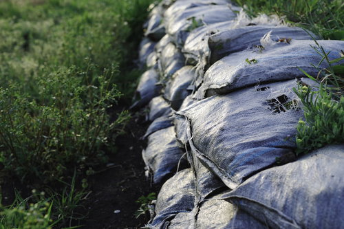 草が生えた積み上げられた砂袋と防水シート