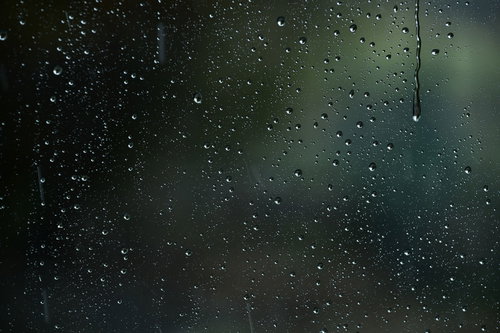 車窓のガラスに降り注ぐ雨と水滴が付着した車内からの景色