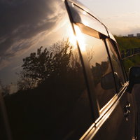 車窓のガラスに映る夕日と木々のシルエットの写真