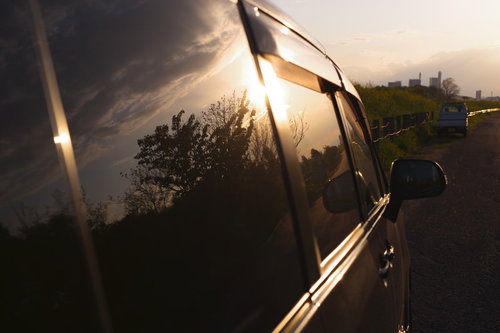 車窓のガラスに映る夕日と木々のシルエット