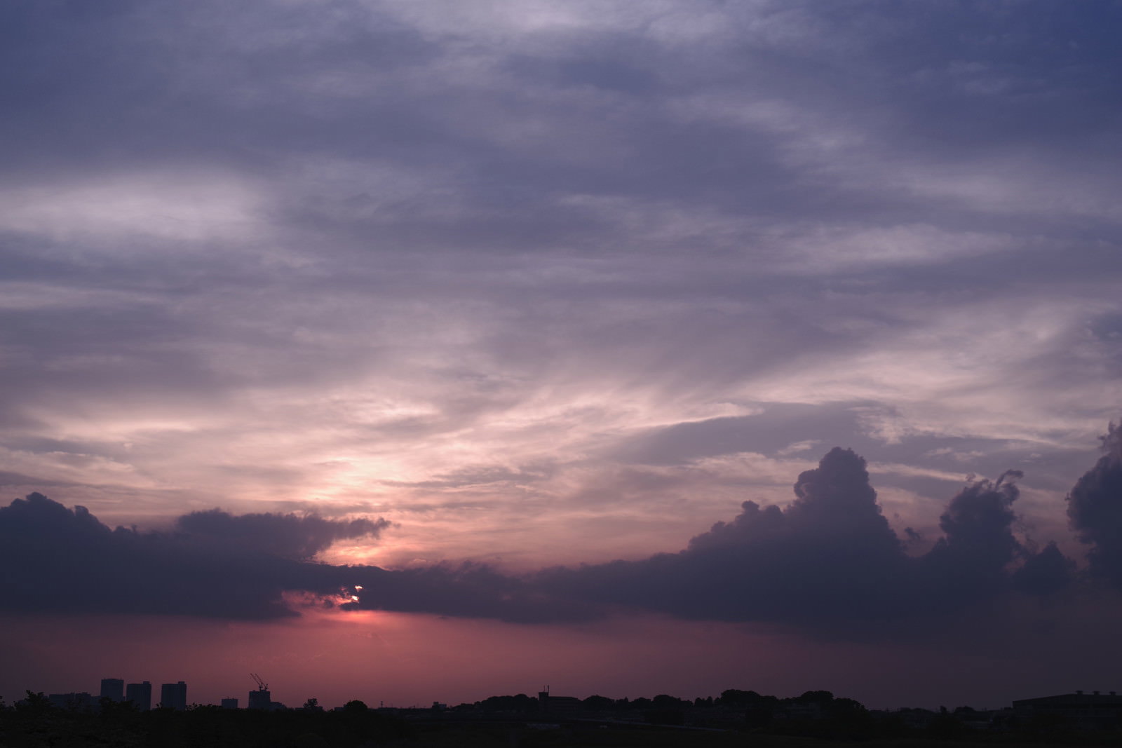 薄紫とピンクの雲が広がる空に沈みかけた夕日