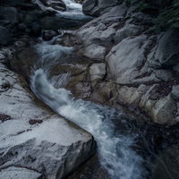 岩場を流れ落ちる日光沢の激流と白い泡の写真