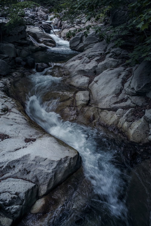 岩場を流れ落ちる日光沢の激流と白い泡