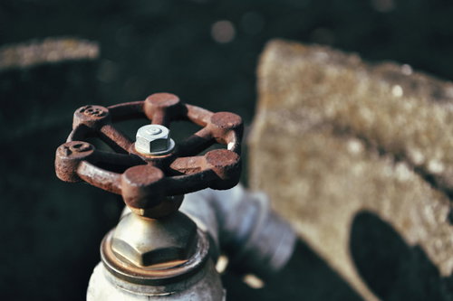 錆びた農水用ポンプの手動弁取っ手と配管設備