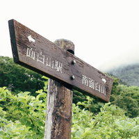 面白山の登山道に立つ木製の道しるべと山並みの景観の写真
