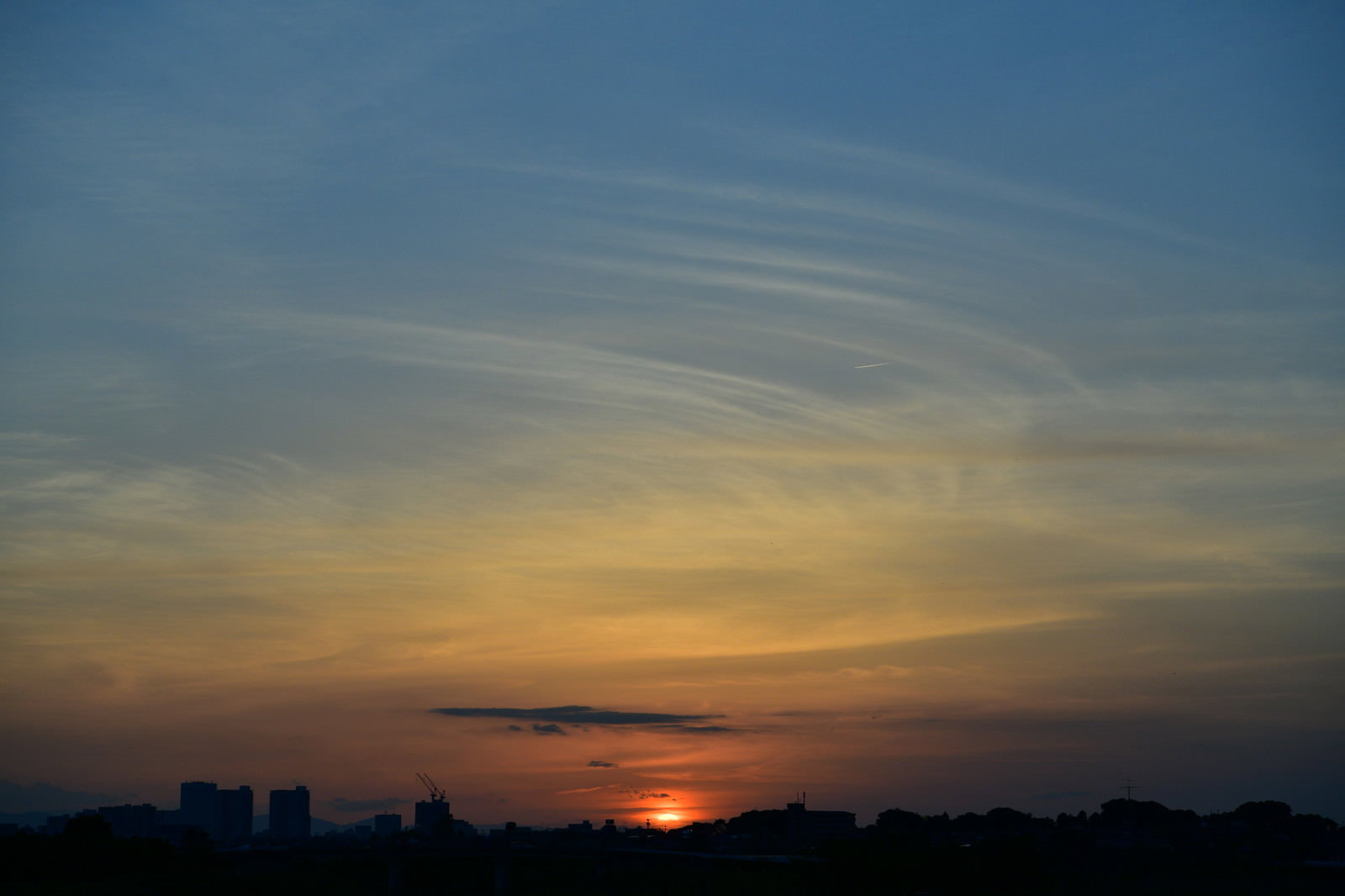水色とオレンジに染まった夕焼け空と地平線に沈む夕日