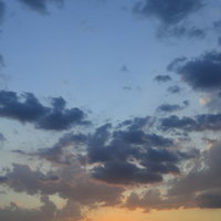 都市の地平線に沈む夕日と水色からオレンジへのグラデーション空の写真