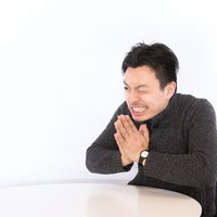 断りづらい一生のお願いをするスーツ姿の男性の写真