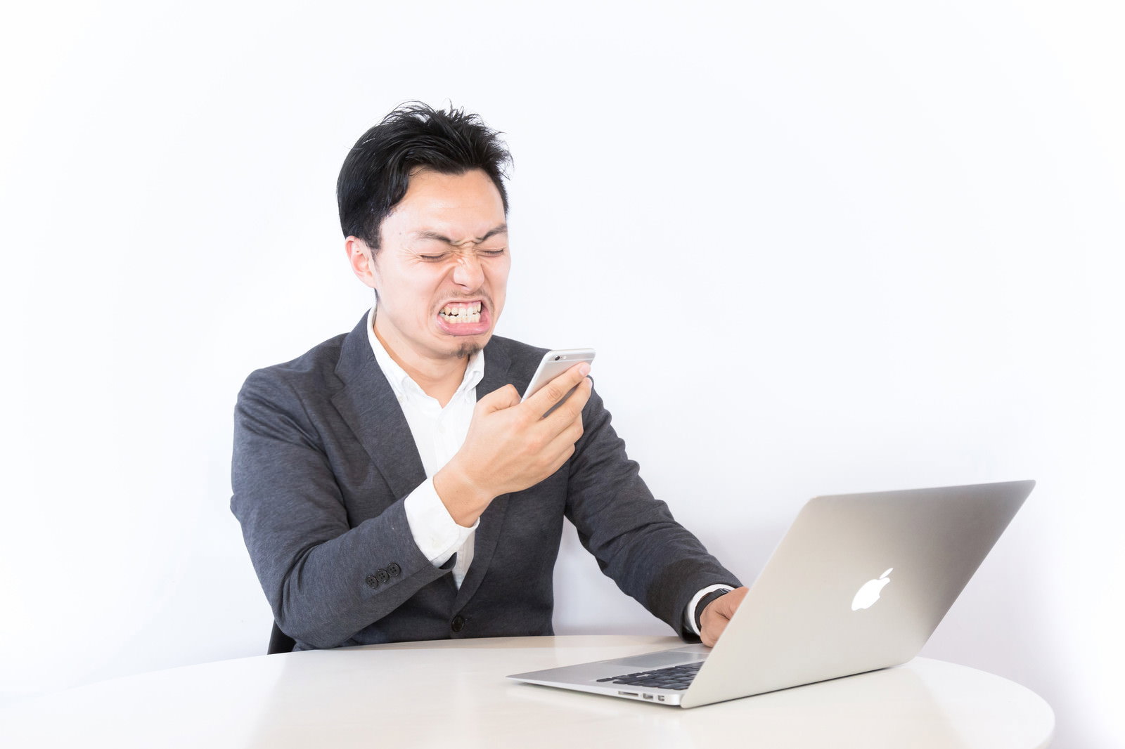 PCを前に険しい表情のビジネスマン［モデル：藤沢篤］