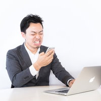 PCを前に厳しい表情のビジネスマンの写真