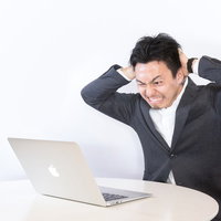 強制決済で頭を抱える男性ビジネスマンの投資損失の写真