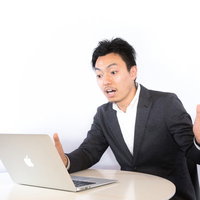 パソコンを見て驚くスーツ男性の写真