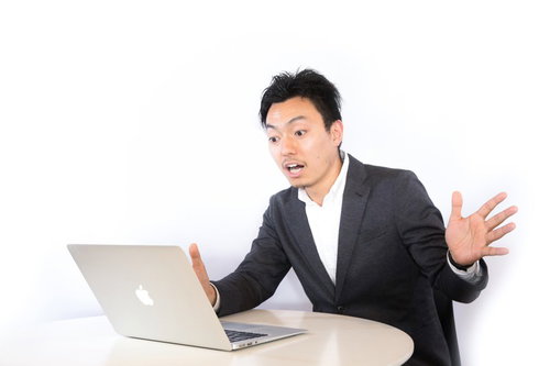 パソコンを見て驚くスーツ男性