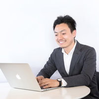 グレーのスーツを着たエンジニアがノートパソコンでリモート作業の写真