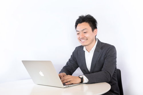 グレーのスーツを着たエンジニアがノートパソコンでリモート作業