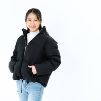 黒いダウンジャケットのポケットに手を入れる女性の写真