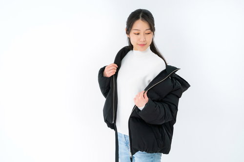 白背景でジャケットを羽織る女性のポーズ・上着の着替え動作