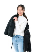 ダウンジャケットを肩にかけるフィッティング中の女性の写真