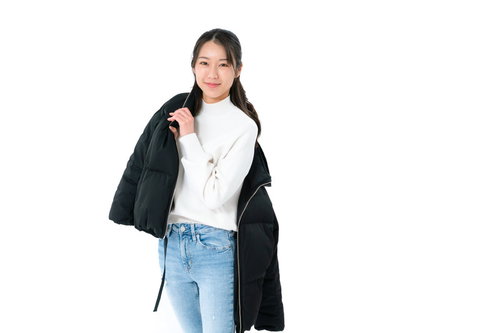 ダウンジャケットを肩にかけるフィッティング中の女性