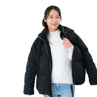 黒いダウンジャケットを羽織る女性の試着ポーズの写真