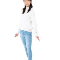 白いトップスを試着するカジュアルな全身ポーズの女性の写真