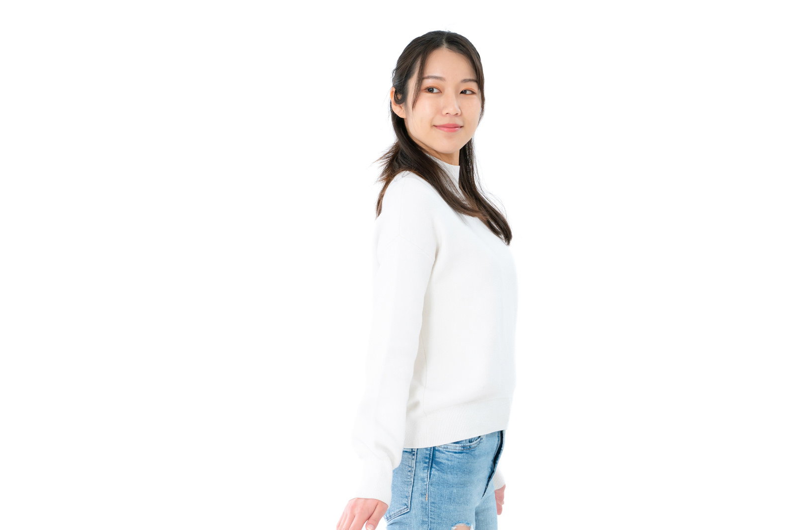 白いトップスとデニムパンツを着た女性が右方向を振り返っている［モデル：SAKI］